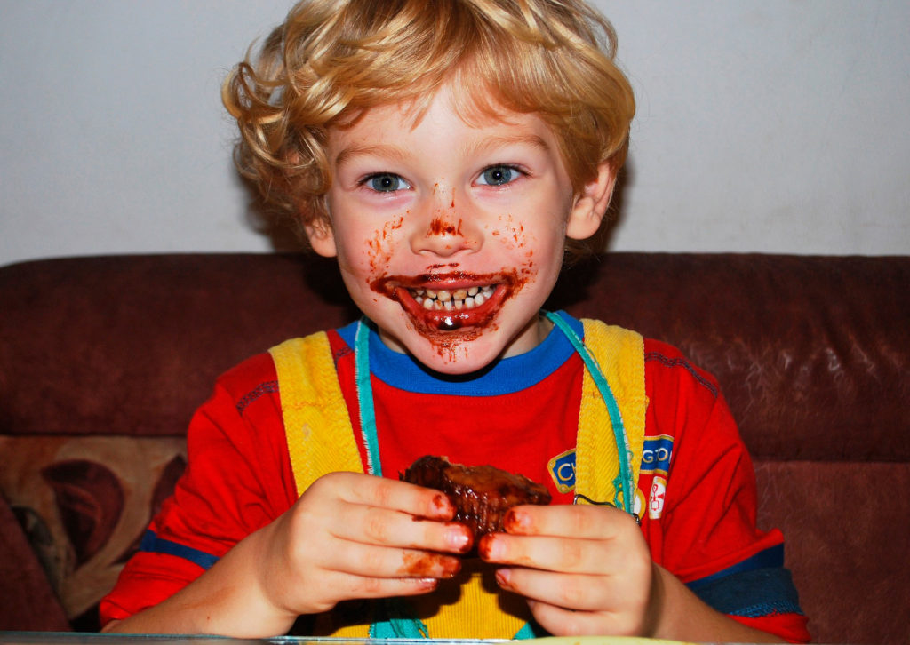 Niño sonriente comiendo chocolate, luz dura de flash